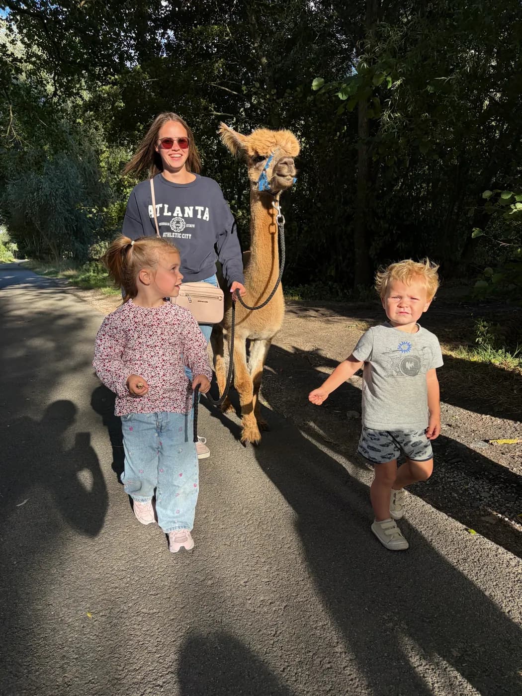 Een gezin met twee kinderen op pad met een alpaca